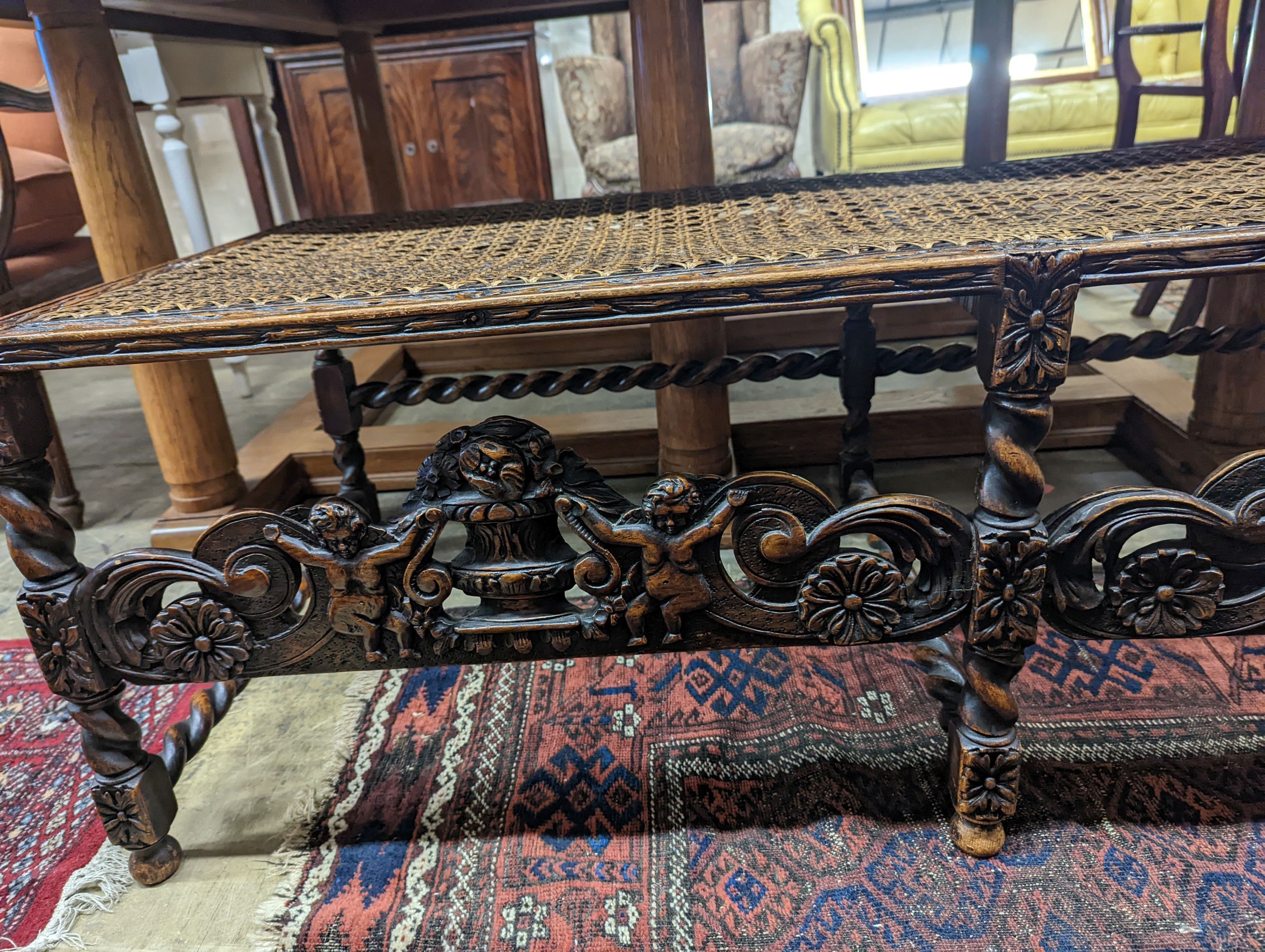 A 1920's Carolean style oak and cane work window seat, length 130cm, depth 58cm, height 44cm